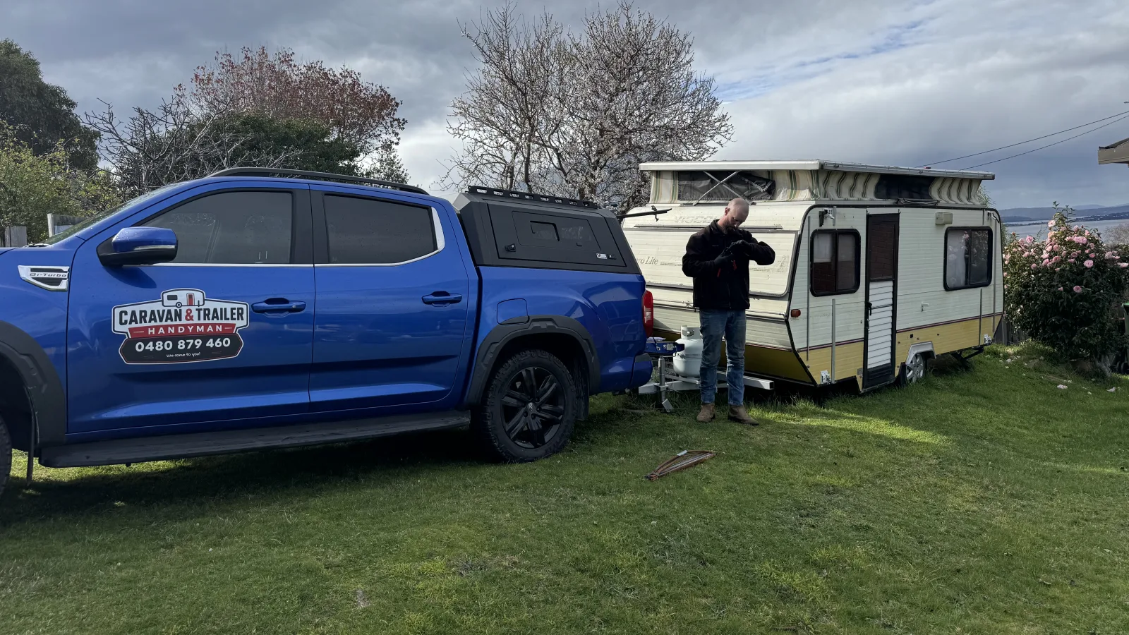Caravan and Trailer Handyman ute parked beside a pop-top caravan on a lawn during a mobile service